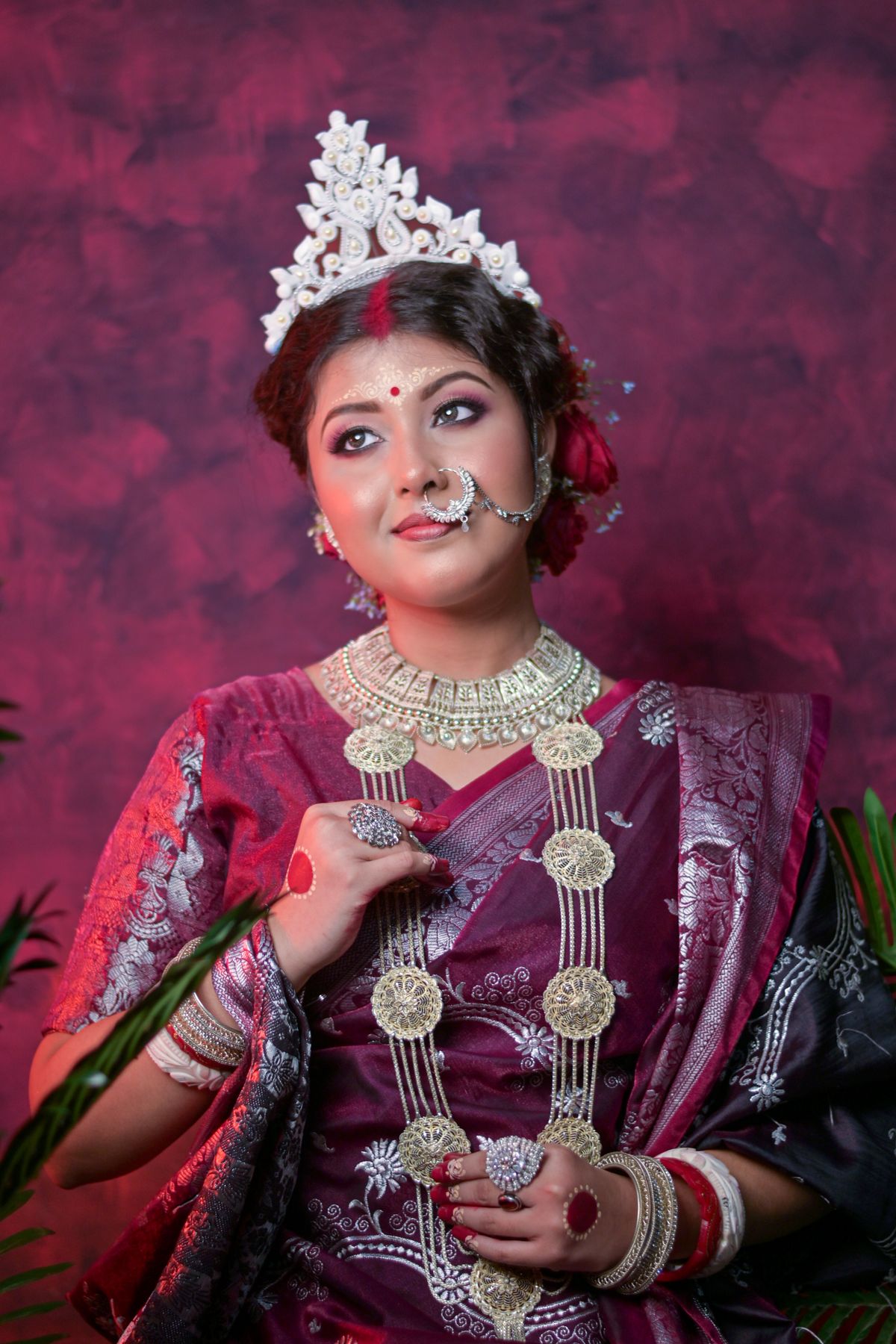 Bride in a maroon zari-woven saree with a traditional bridal crown