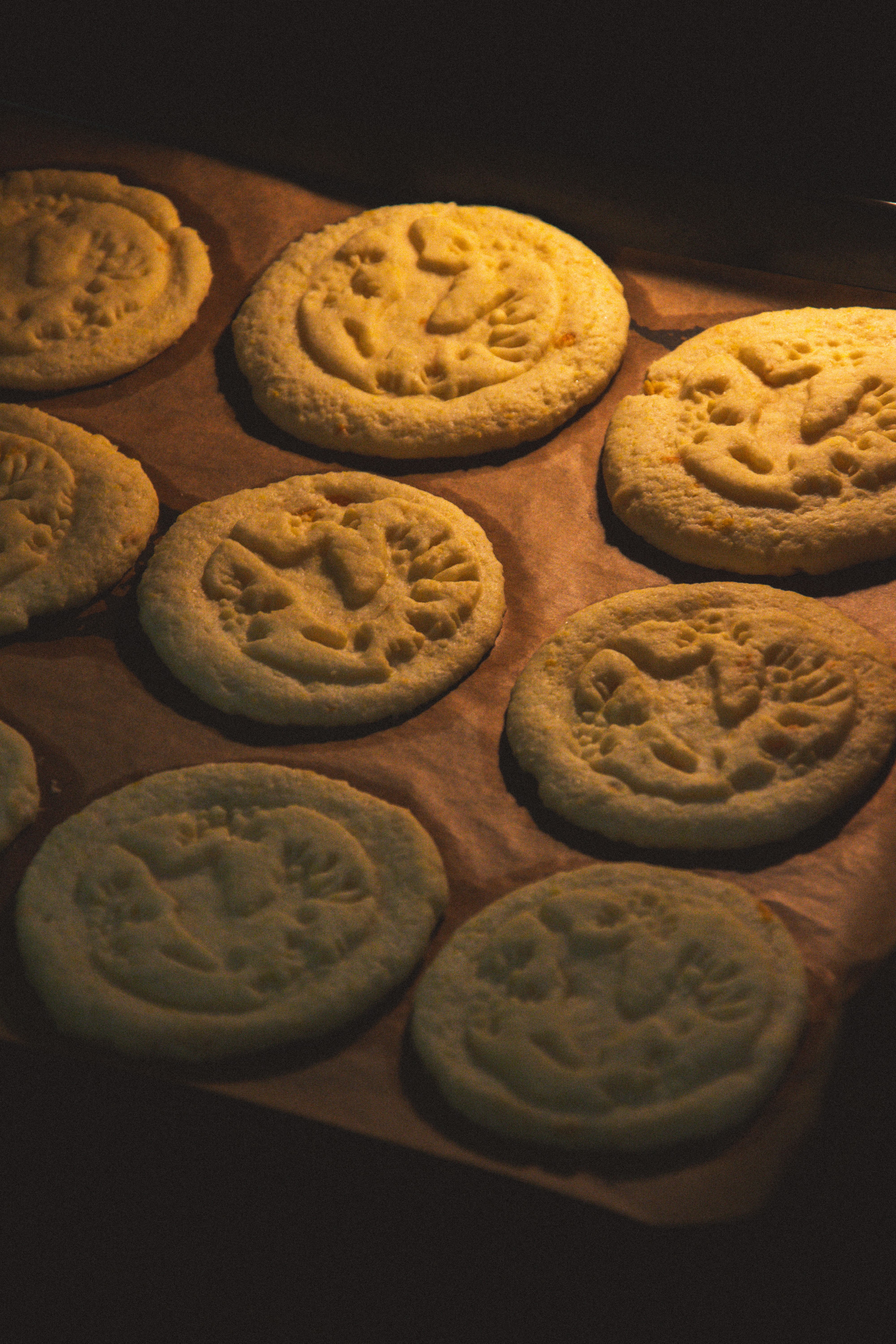 Warm sugar cookies with Christmas themed imprints baking in an oven, creating a cozy holiday feel.