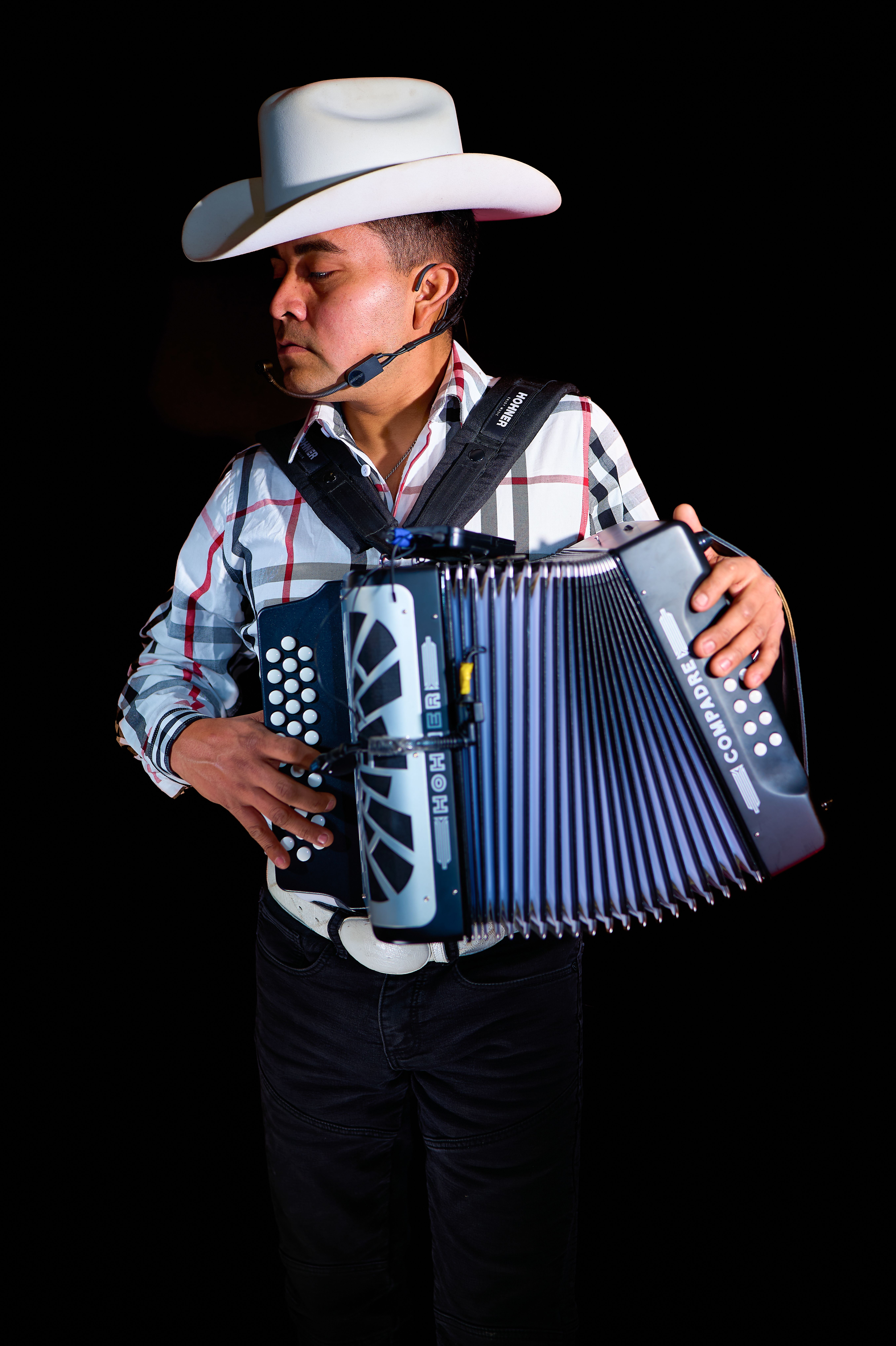Caucasian man wearing cowboy hat plays accordion with focus and skill.