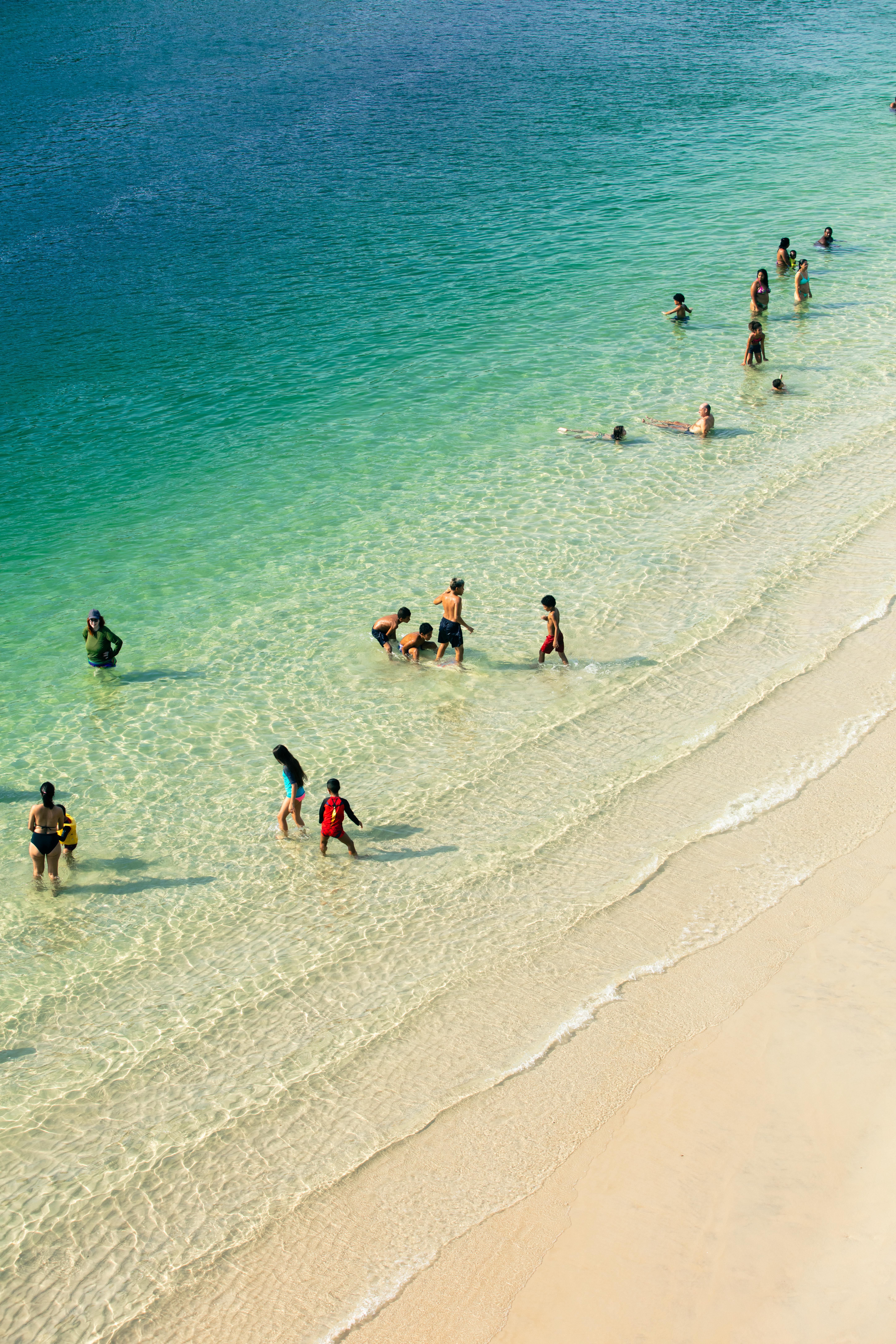 Young children wading in the calm shallow water at Nusa Dua beach in Bali