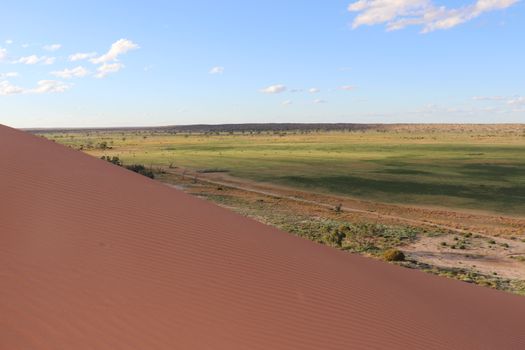 Expansive landscape view from a sand dune in Australia, showcasing arid and green terrains.