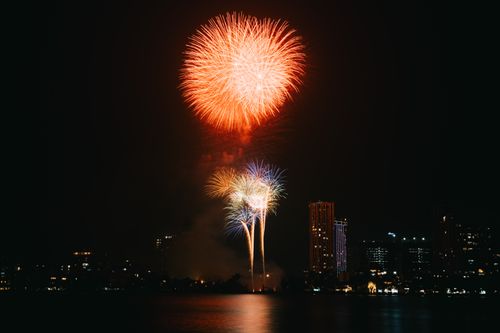 Free Vibrant fireworks illuminate a city skyline at night, reflecting on the water. Stock Photo