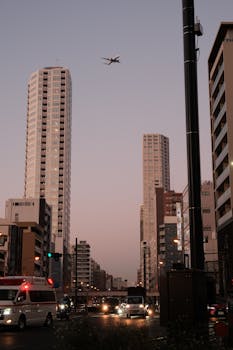 Captivating view of Tokyo street at twilight with skyscrapers and airplane high above.