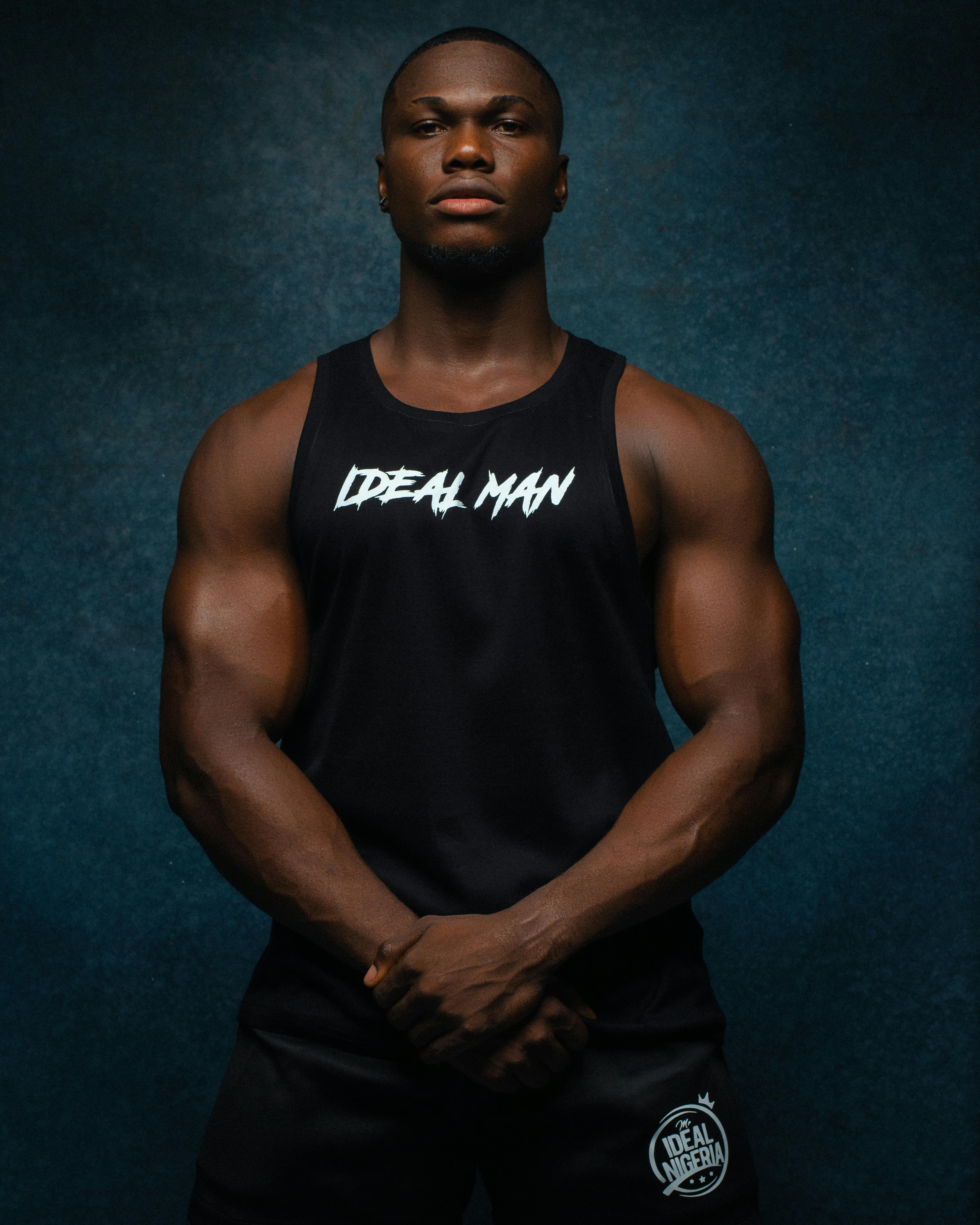 bezplatná Silný portrét svalnatého afrického muže v tílku s nápisem „Ideální muž“. Základová fotografie