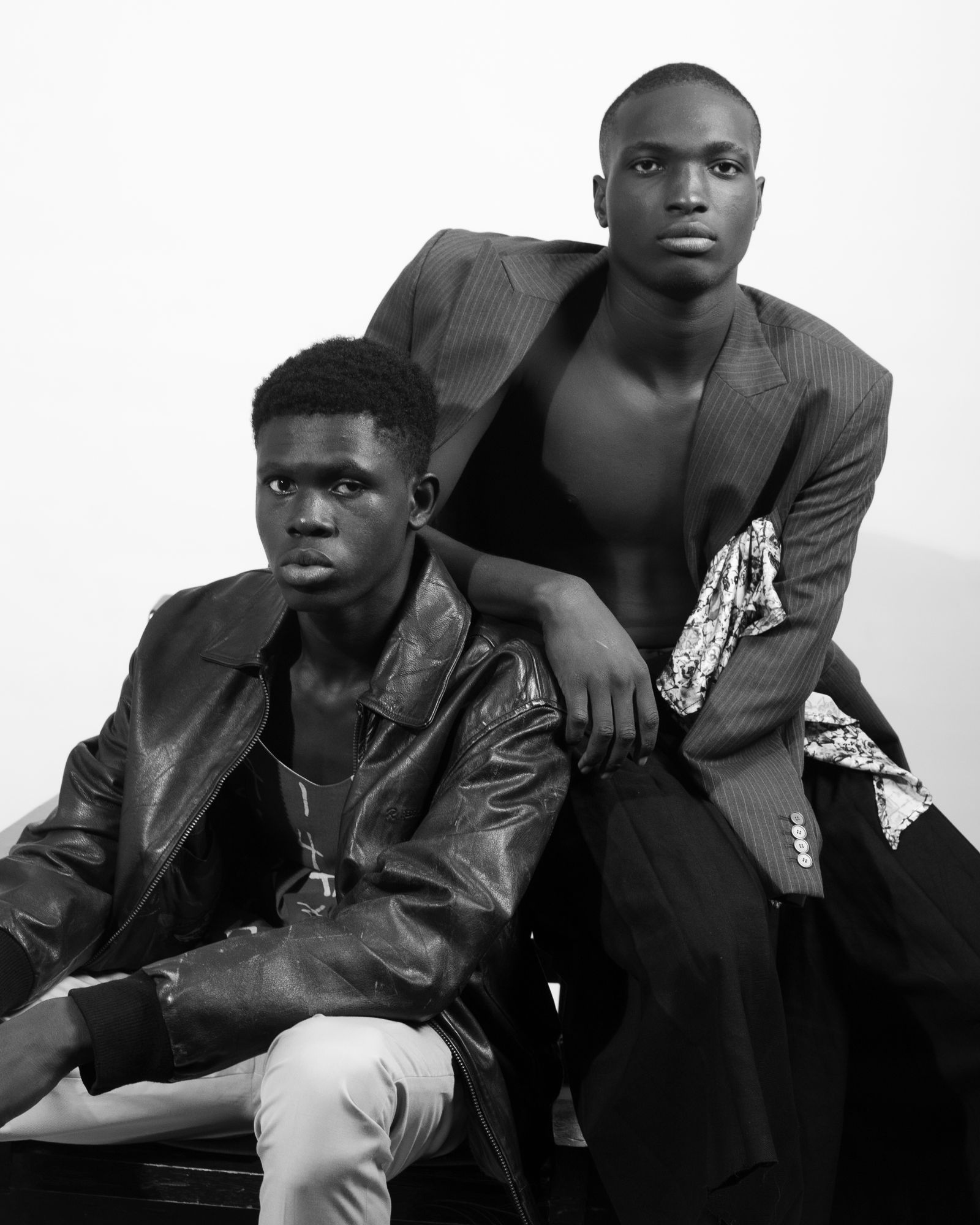 A high-contrast black and white fashion editorial portrait of a model in a fitted suit.