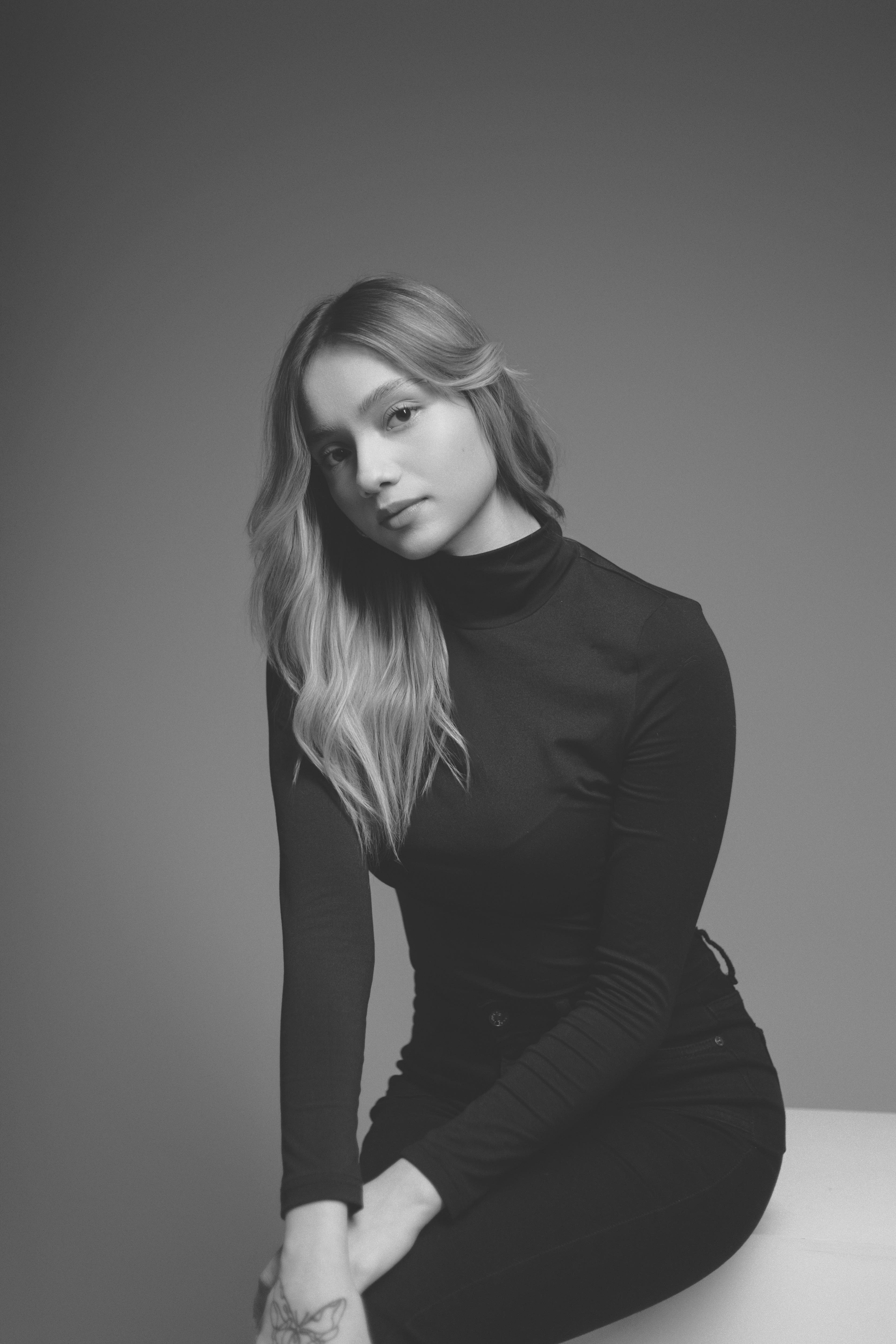 De franc Elegant retrat en blanc i negre d'una dona asseguda sobre un fons llis. Foto d'estoc