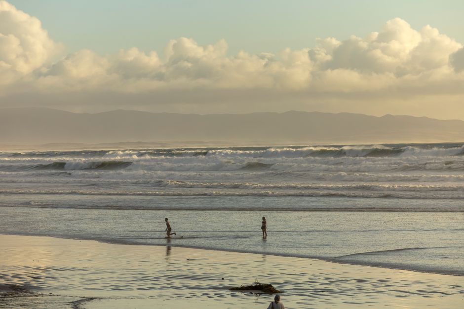 A peaceful beach scene with gentle waves and children playing, evoking tranquility.