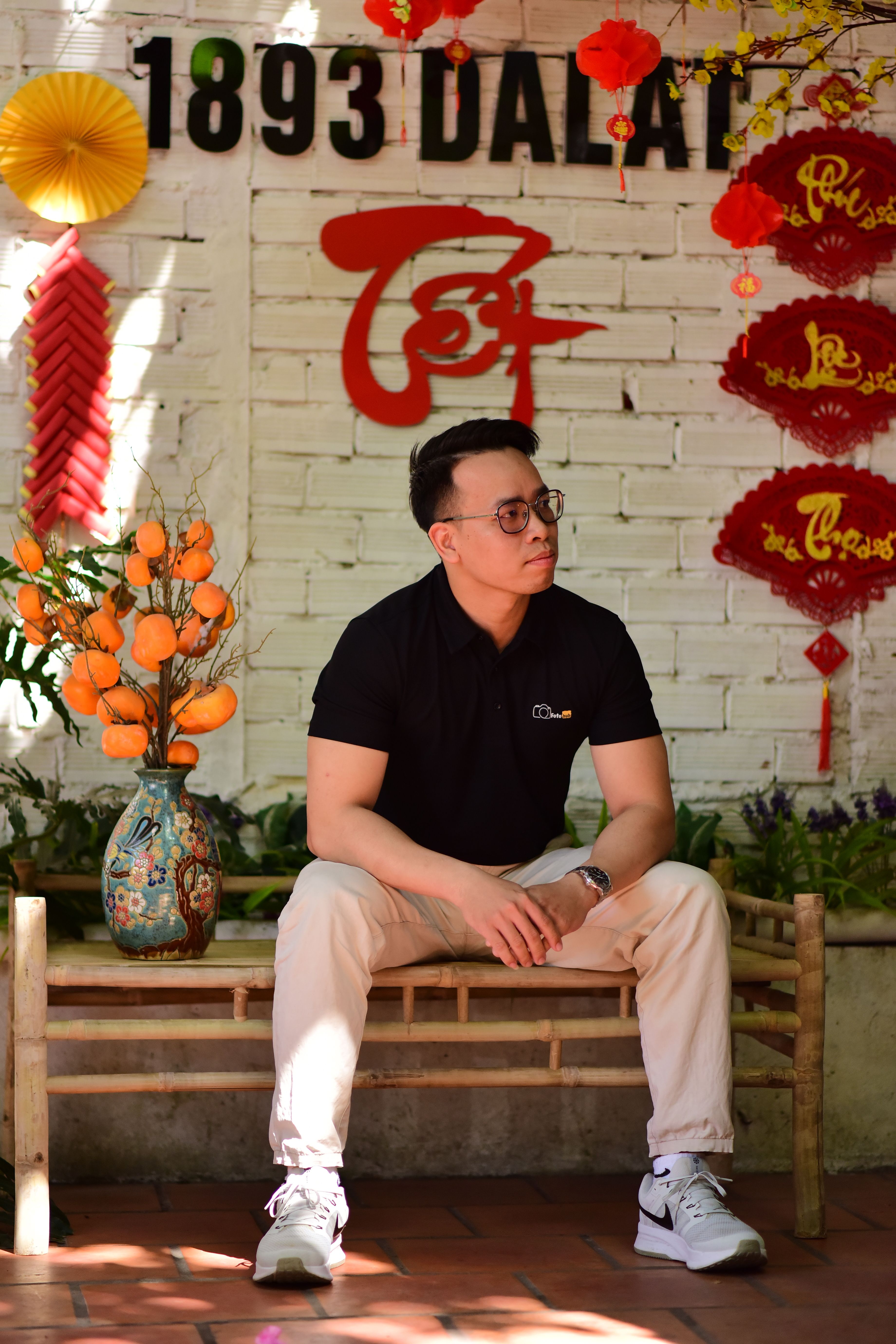 A man sits in front of Vietnamese New Year decorations, featuring vibrant colors and festive ambiance.