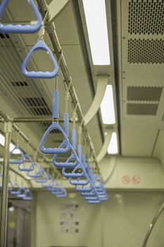 Empty train interior featuring blue triangular grab handles, showcasing modern public transport design.
