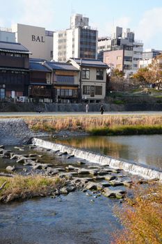 Picturesque Kyoto riverside in autumn showcasing traditional architecture and tranquil waters.