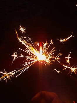 Close-up of a sparkler glowing brightly in the dark, creating festive sparks.