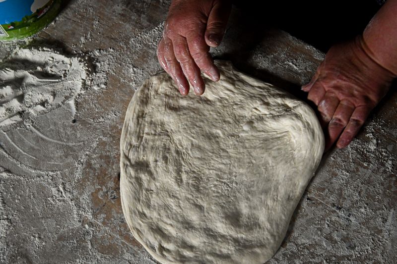 Close-up of hands kneading dough on a floured surface, showcasing homemade baking.