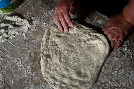 Close-up of hands kneading dough on a floured surface, showcasing homemade baking.