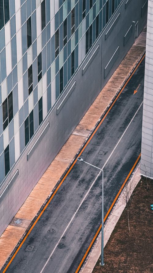 Free Aerial view of a modern urban alleyway flanked by tall glass buildings. Stock Photo