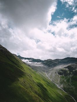 Breathtaking view of lush green mountains under dramatic cloudy sky.