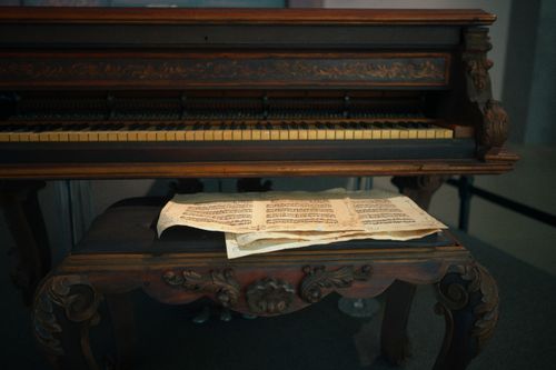 Free Elegant vintage piano with ornate carvings and classic sheet music on bench. Stock Photo