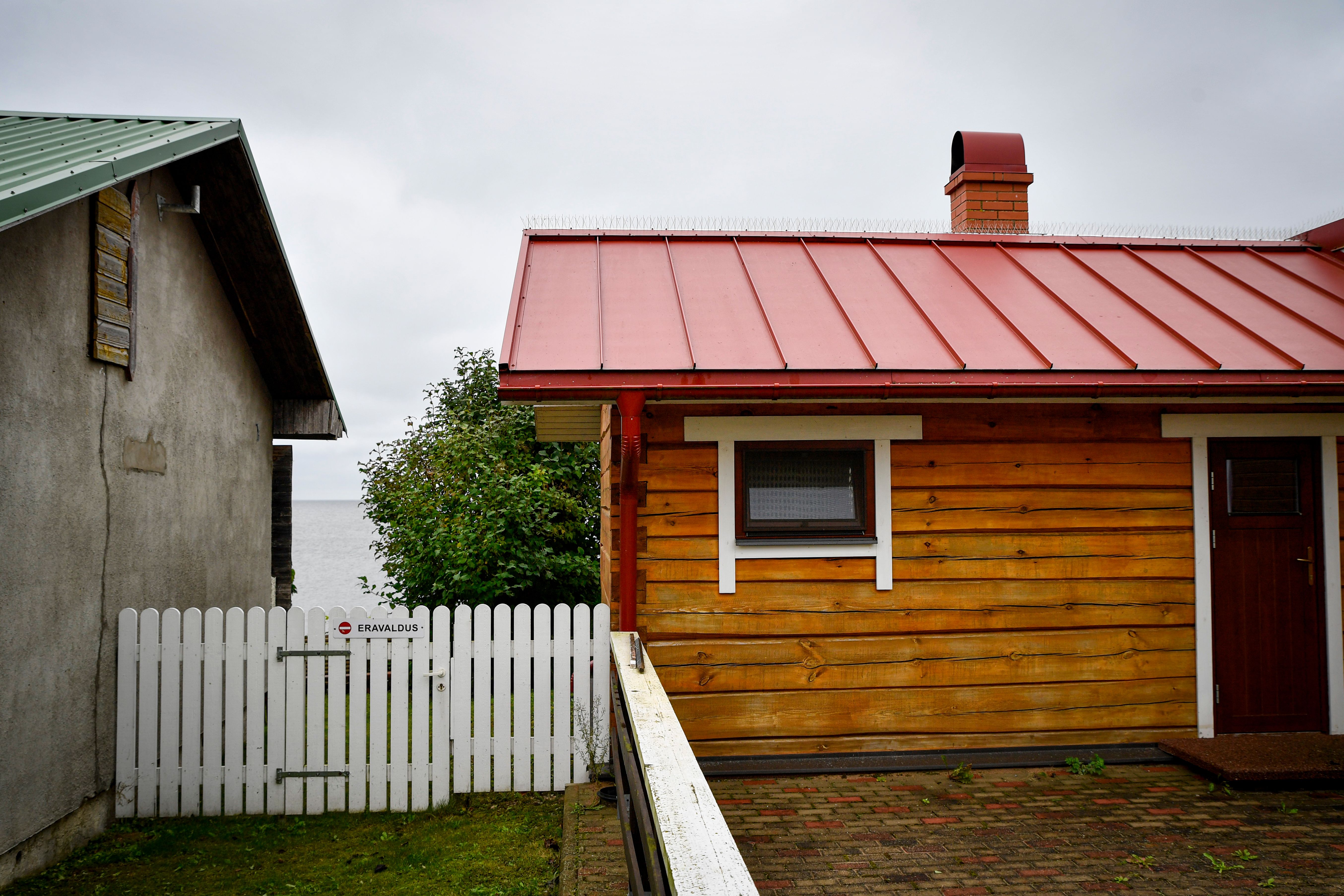 A quaint wooden house with a red roof near Lake Peipsi in Tartu County, Estonia.