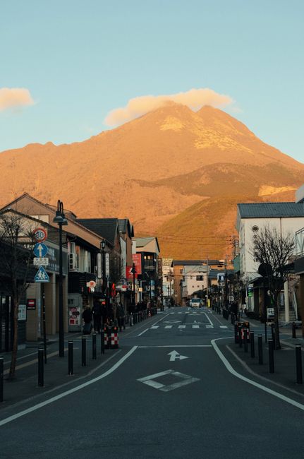 Serene street with urban architecture against stunning mountain backdrop at sunset.
