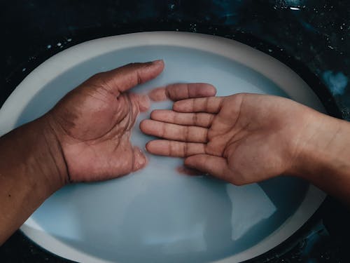 Person's Hand on White Ceramic Sink