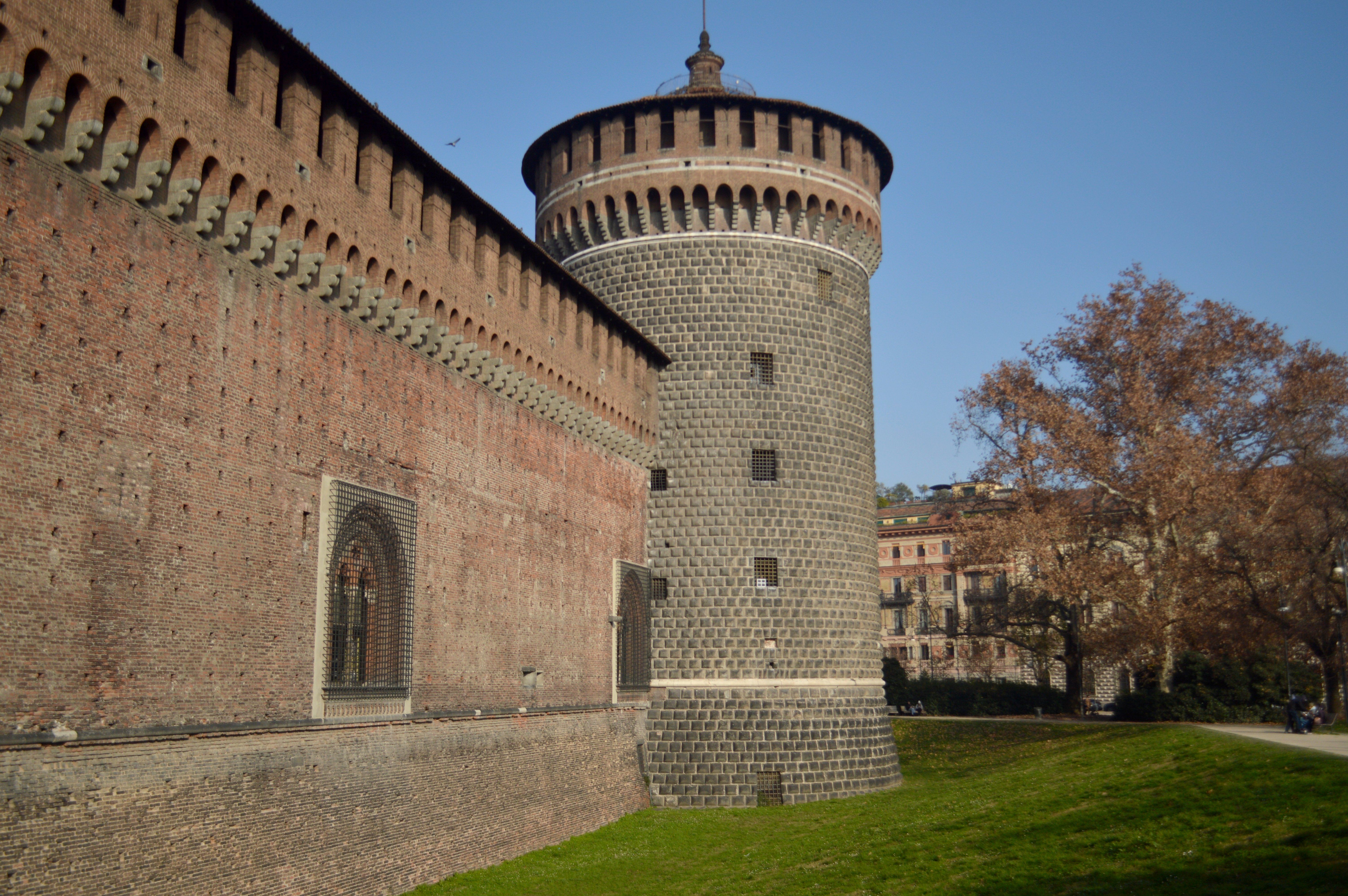 View of the historic Sforza Castle in Milan, showcasing its medieval architecture under a clear blue sky.
