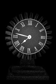 Stylish black clock with Roman numerals against a dark background.