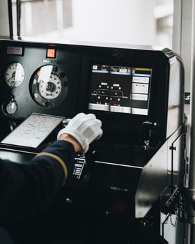 A train driver operates modern train controls with precision, showcasing interior technology.