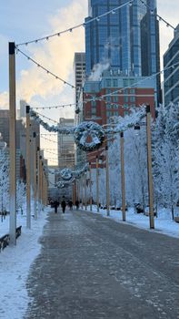 Snow-covered urban street adorned with holiday decorations and lights.