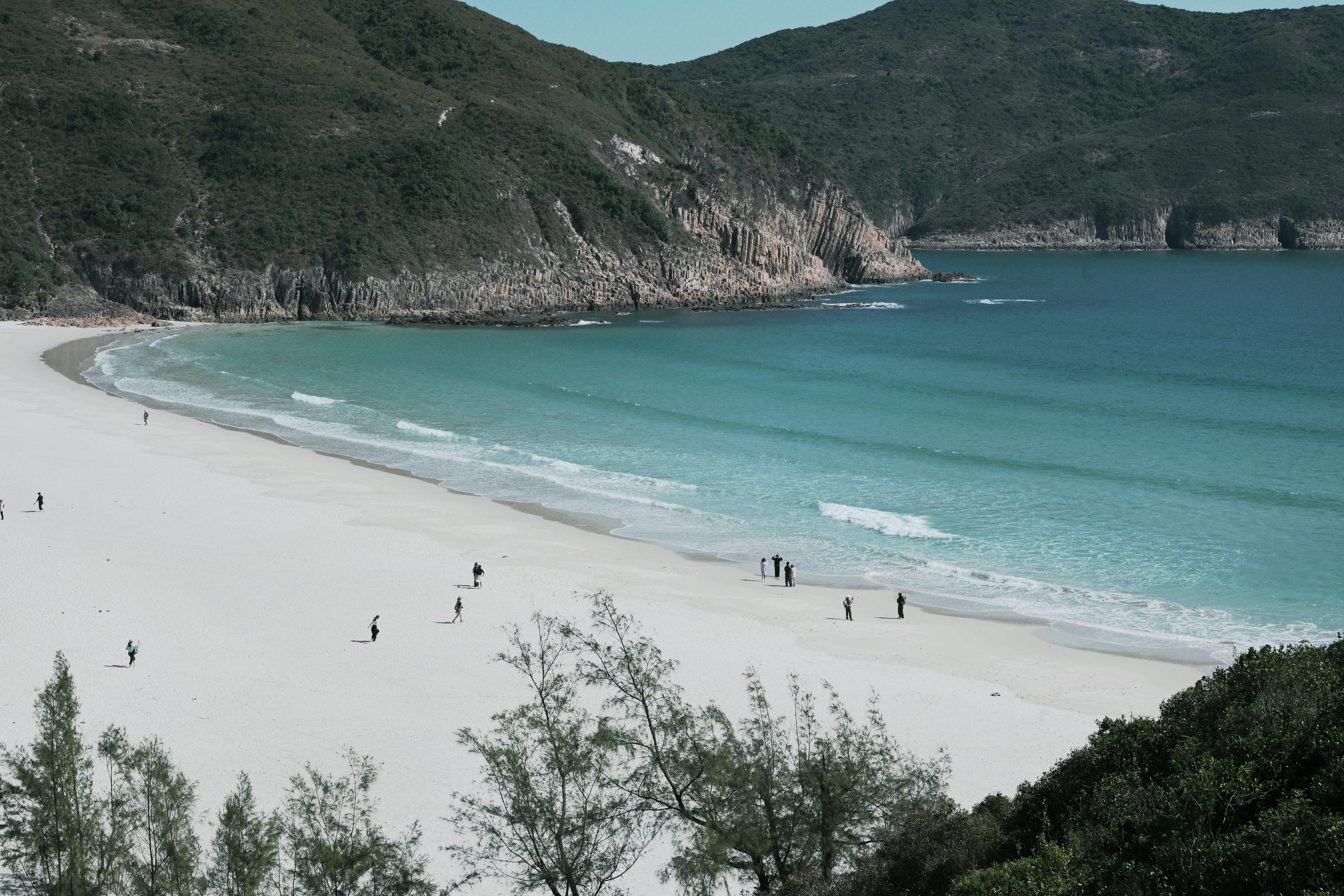 A tranquil beach scene with turquoise waters and people enjoying the sandy shore.