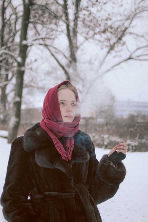 Free Woman in fur coat and red scarf smoking outdoors in winter. Stock Photo