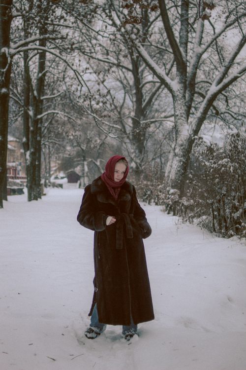 Free A woman in a warm coat walks through a snow-covered park in winter. Stock Photo