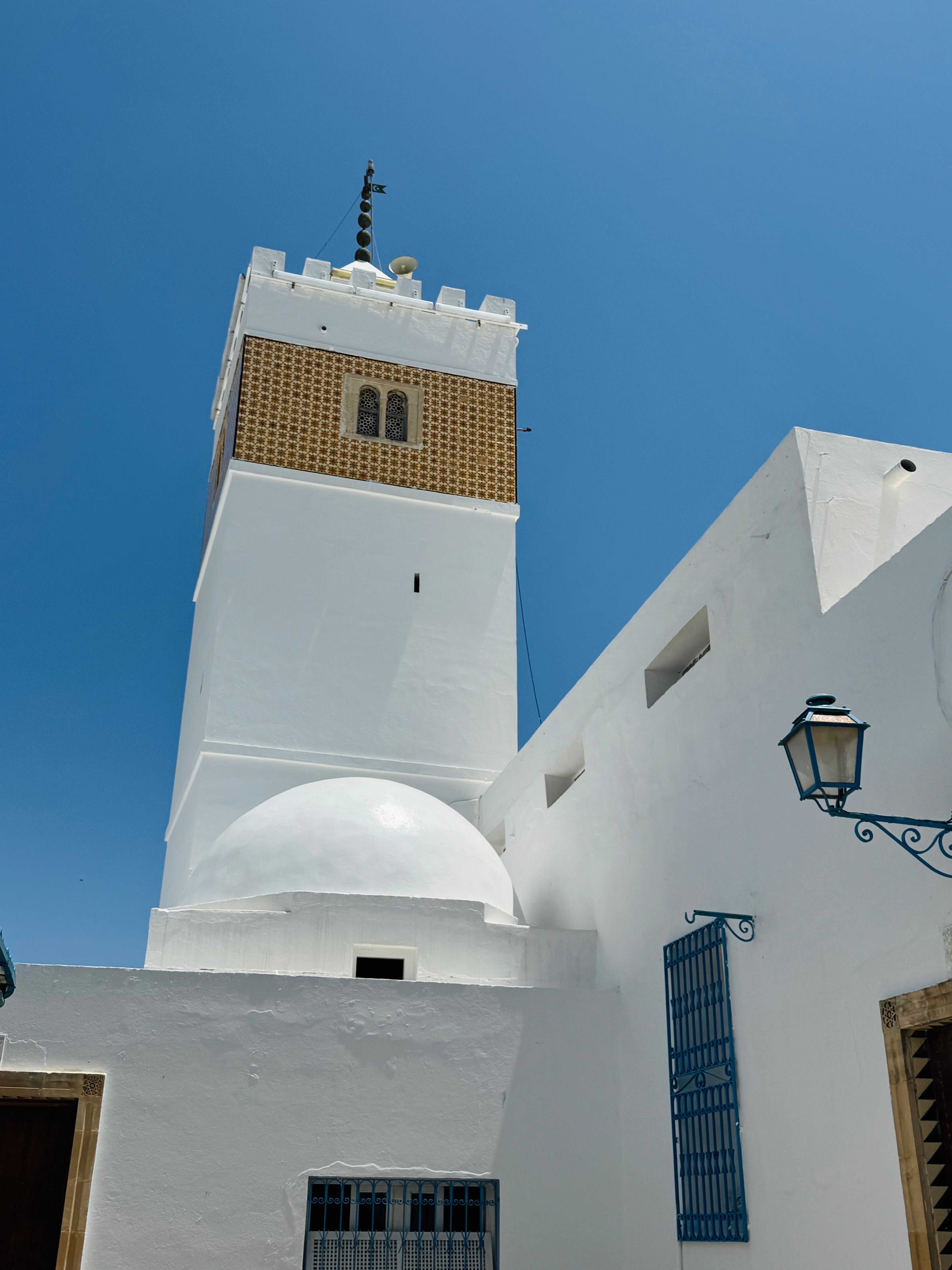 Beautiful white minaret against a clear blue sky in Hammamet, Tunisia.