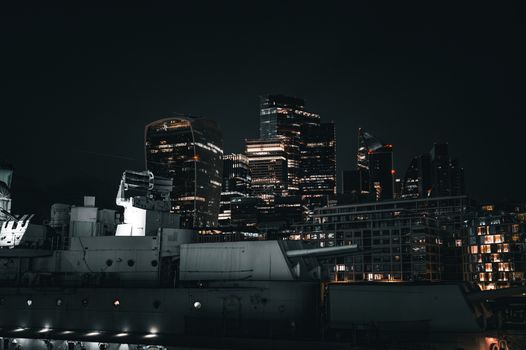 Stunning view of the London skyline at night, featuring a silhouetted battleship and illuminated buildings.