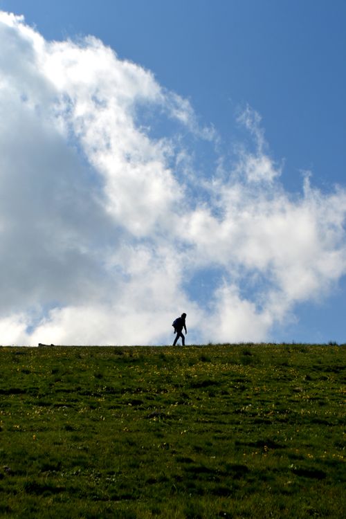 Free A lone hiker's silhouette against a cloudy sky on a scenic grassy hill. Captured with NIKON D3100. Stock Photo