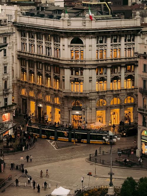 Free A vibrant evening in Milan's historic district showcasing classic architecture and a lively tram. Stock Photo