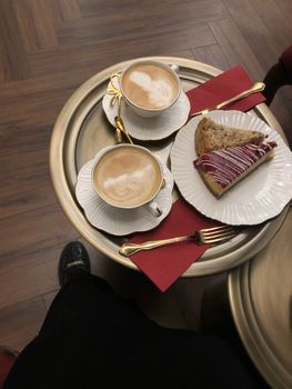 Two cappuccinos and a pastry on a table for a cozy café experience.