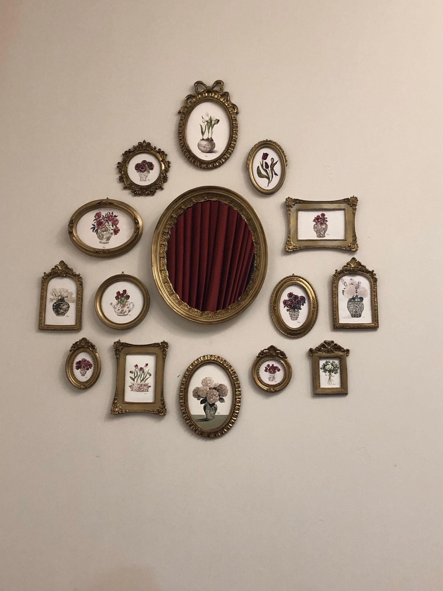 Gold-colored floral picture frames arranged around a large oval mirror
