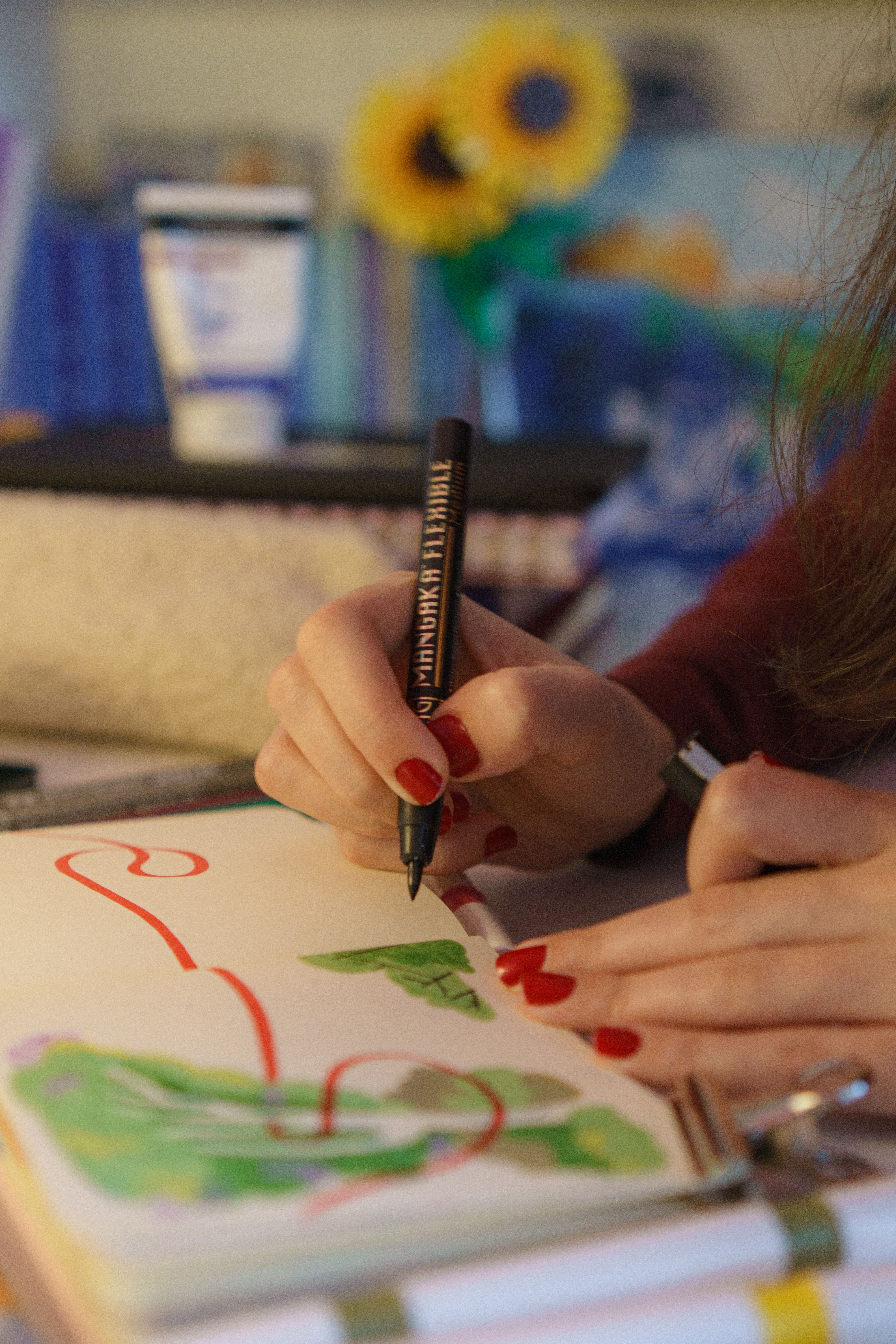 Woman illustrating in notebook with vibrant colors and focus on details.