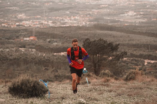 Man running on a mountain trail with scenic landscape in the background.