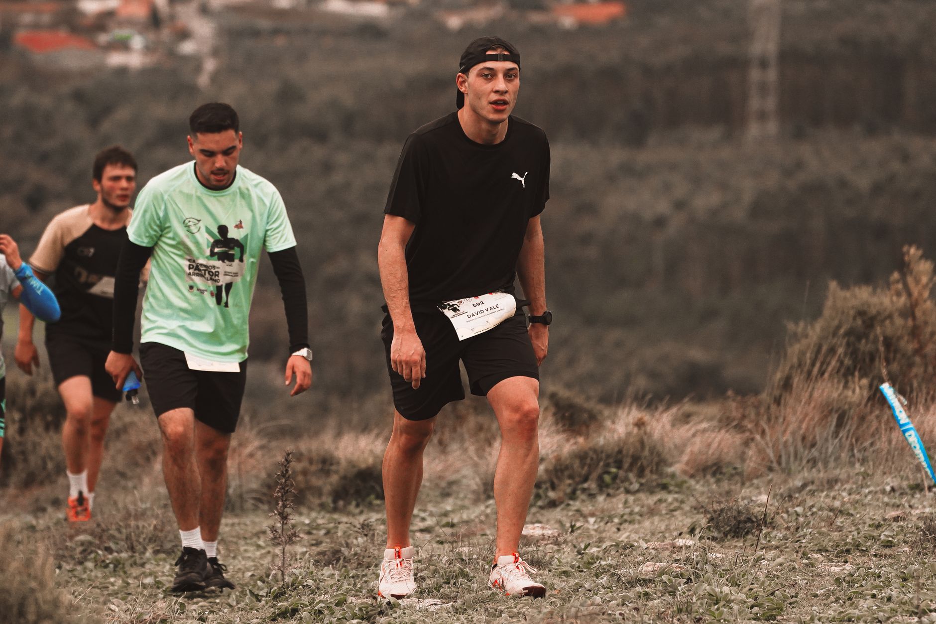 Men running together on a grassy trail