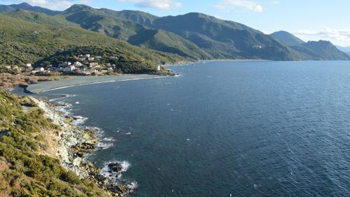 Free Breathtaking aerial view of Ogliastro's coastline with mountains and village in Corsica, France. Stock Photo