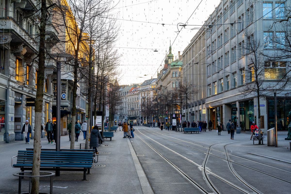 Bahnhofstrasse at dusk, trams and pedestrians passing historic facades near Paradeplatz.