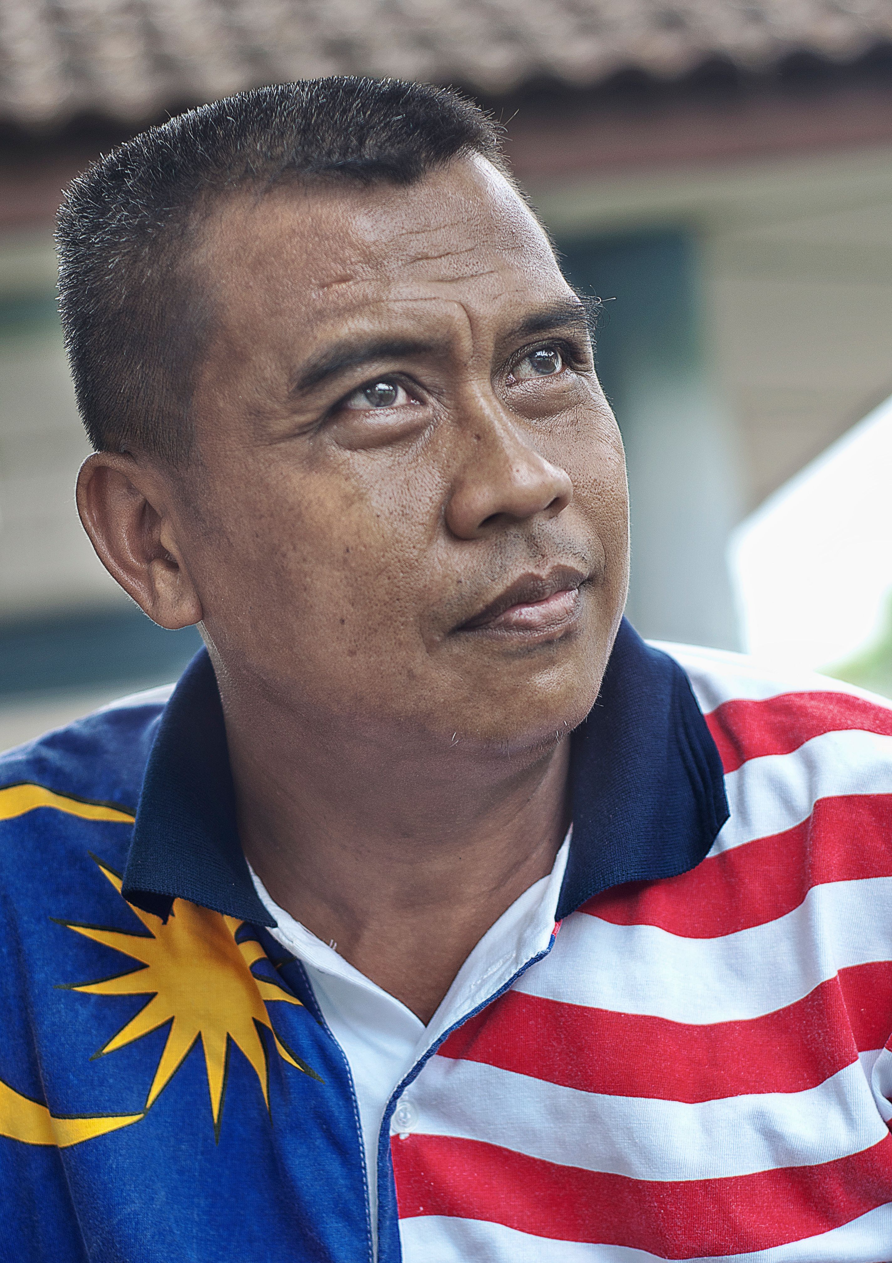 Portrait of a man wearing a Malaysian flag shirt, expressing pride.