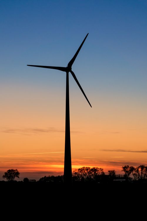 Free A lone wind turbine silhouetted against a vibrant sunset sky, symbolizing renewable energy. Stock Photo