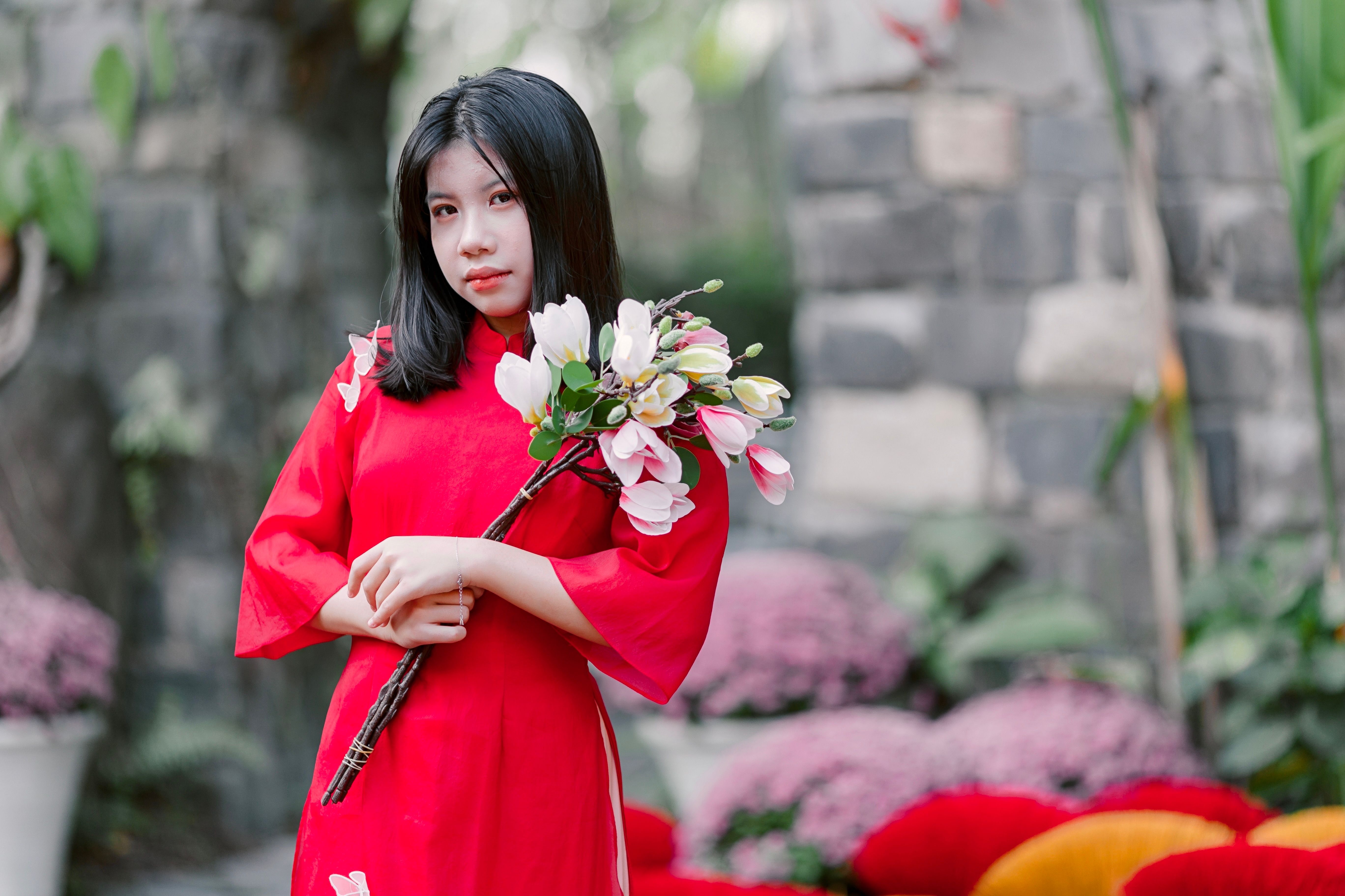 Young Woman in Red Dress Holding Flowers Outdoors · Free Stock Photo