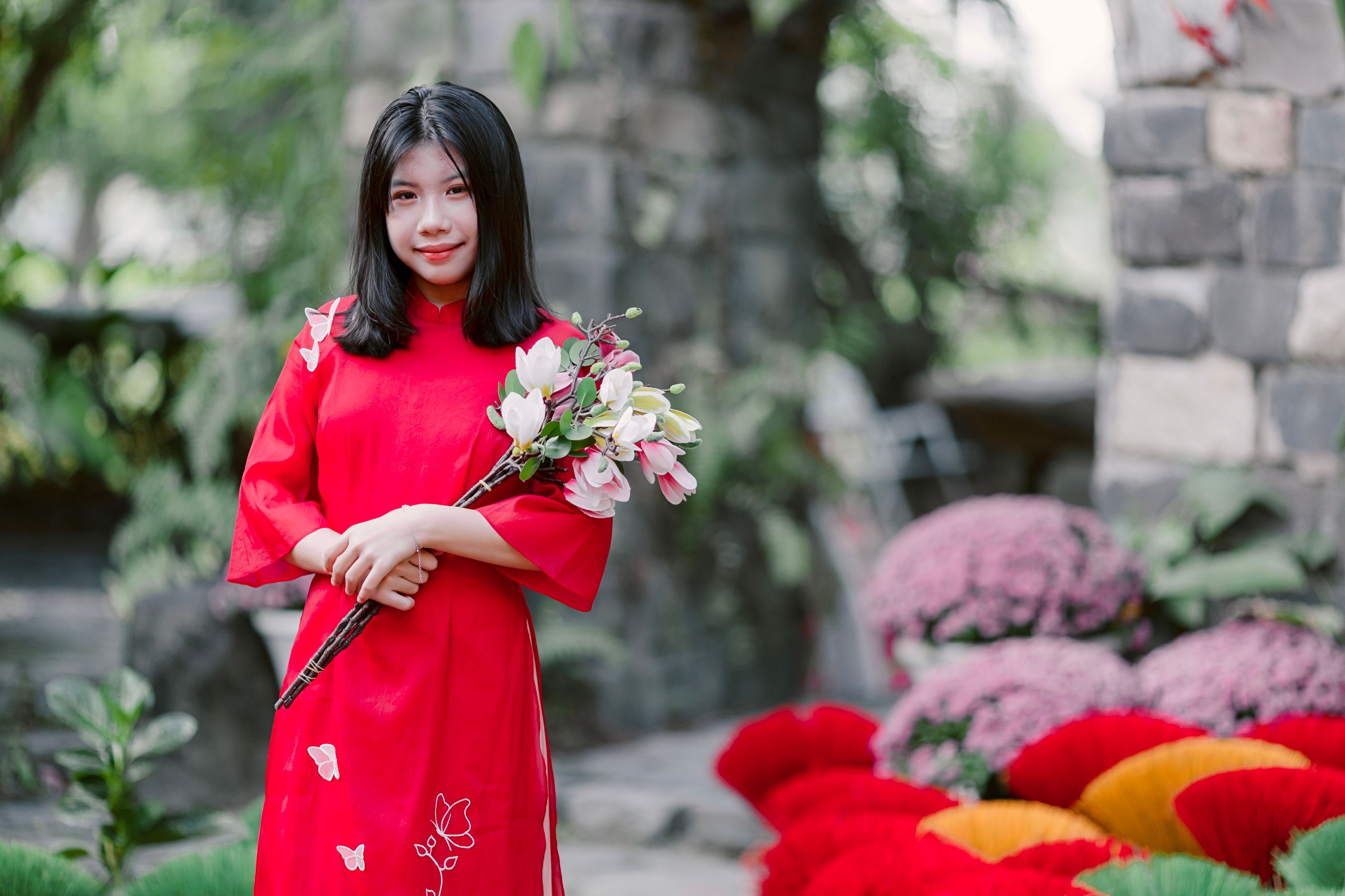 Young Woman in Traditional Red Dress Holding Flowers · Free Stock Photo