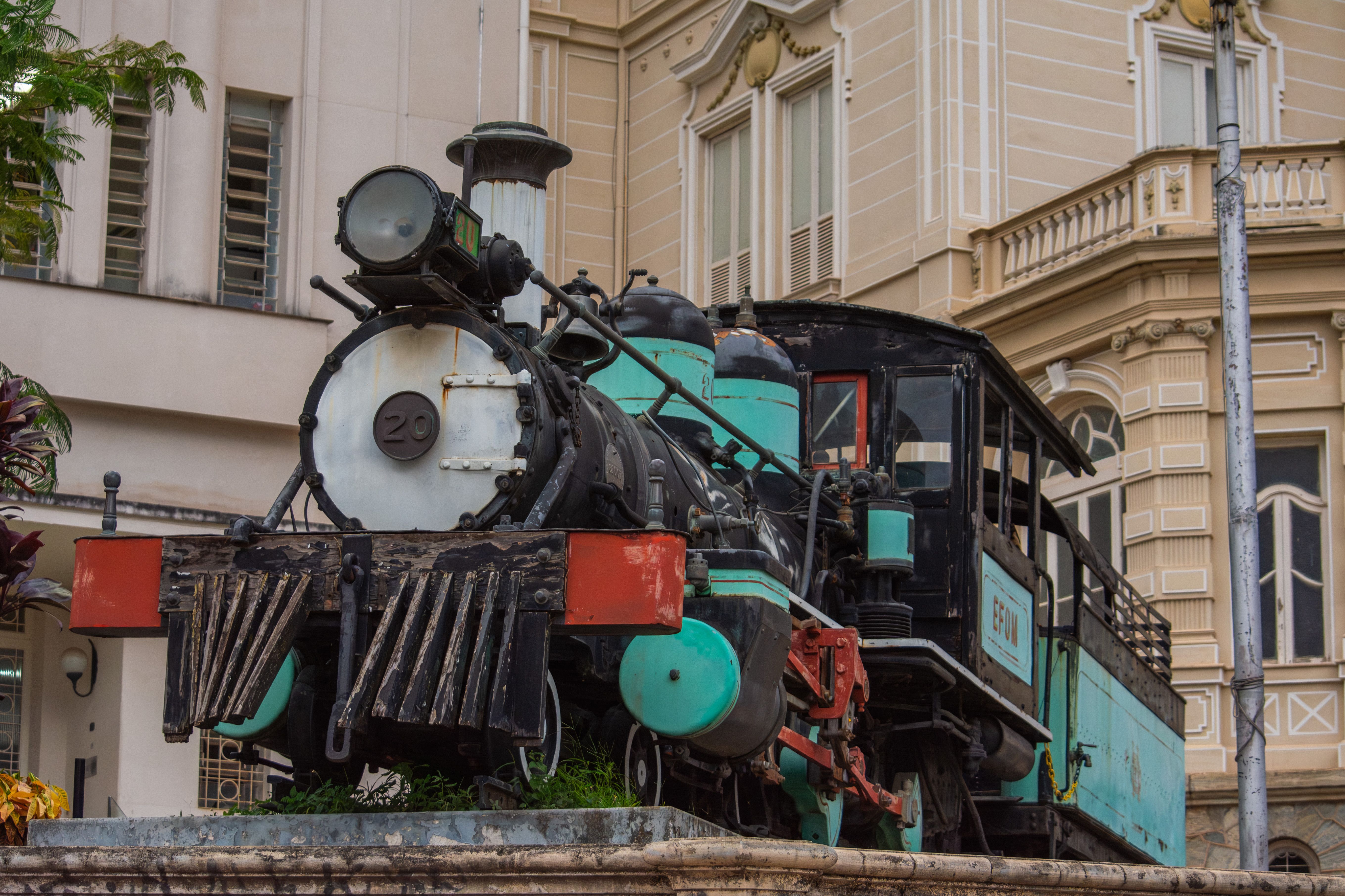 A historic locomotive displayed in Belo Horizonte, Brazil, in front of classic architecture.