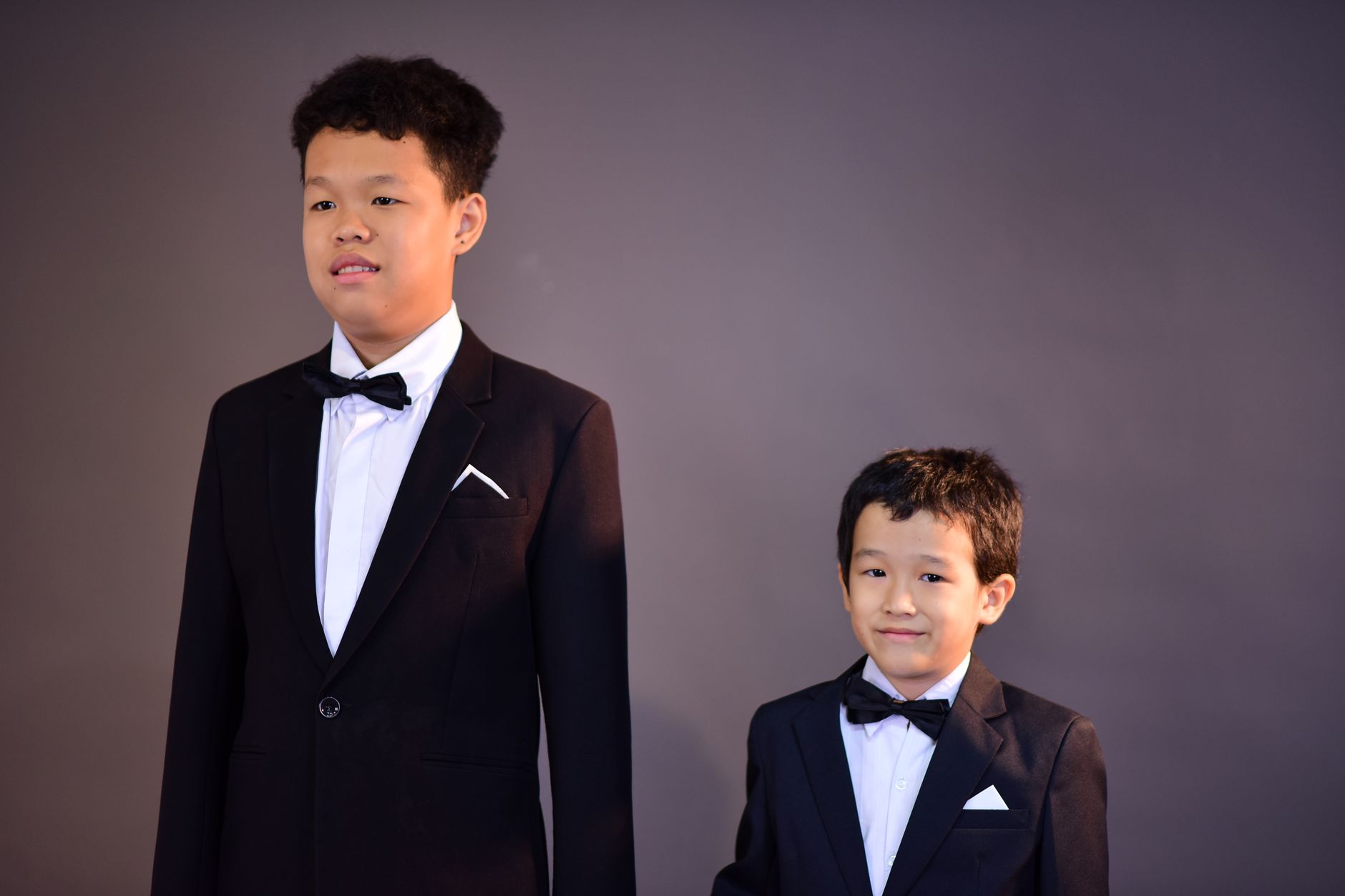 Two boys in elegant suits and bow ties posing for a formal portrait.
