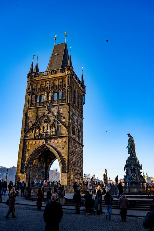 Free The iconic Charles Bridge Tower in Prague against a vibrant blue sky, with people enjoying a day out. Stock Photo