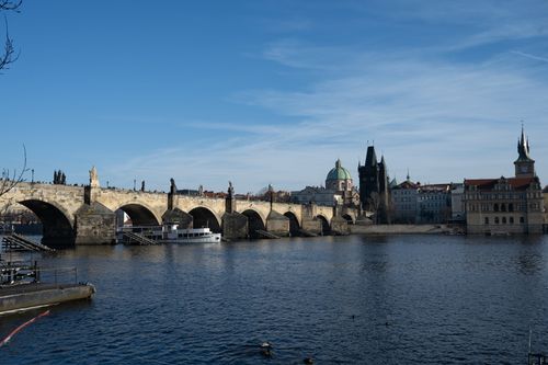 Free A scenic view of the historic Charles Bridge and Vltava River in Prague under a bright blue sky. Stock Photo