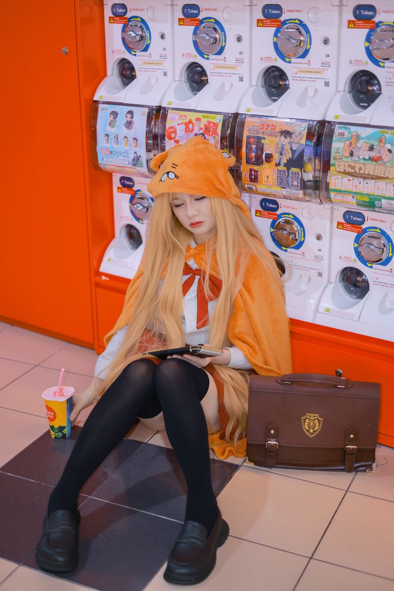A person in cosplay costume sitting by capsule vending machines in Sydney arcade.